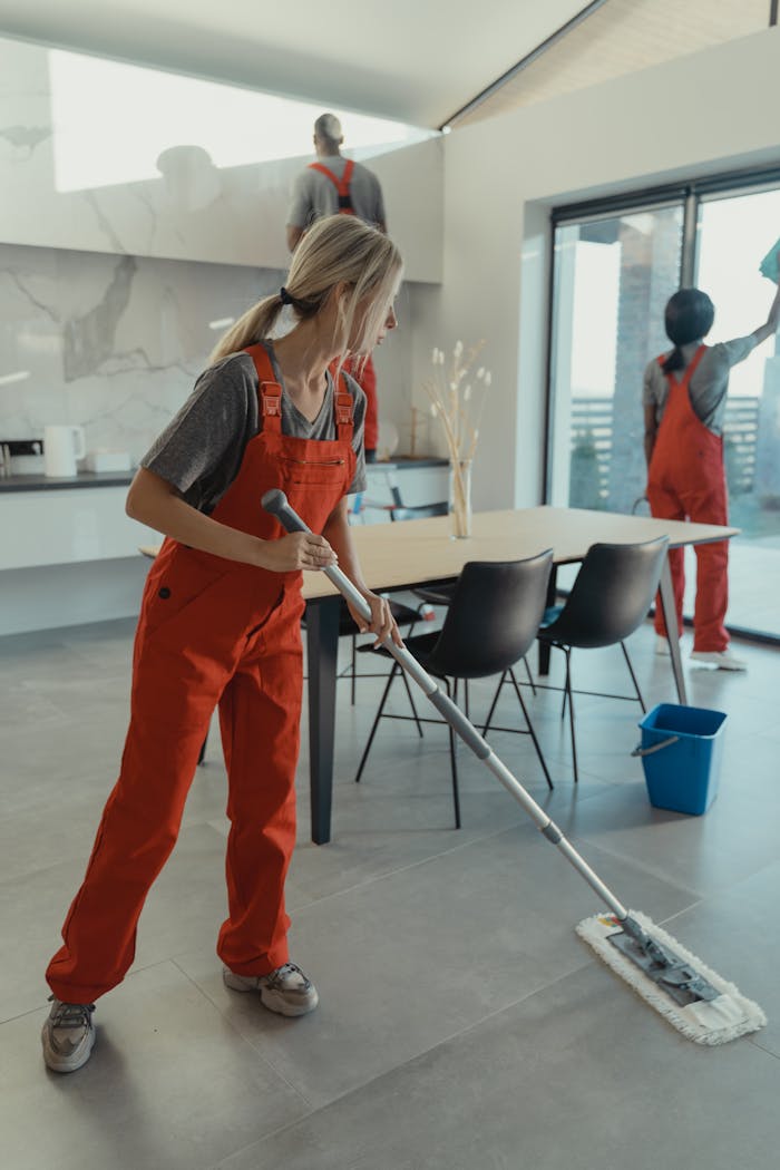 about-01 Cleaning team in red overalls mopping and sanitizing a modern home interior.